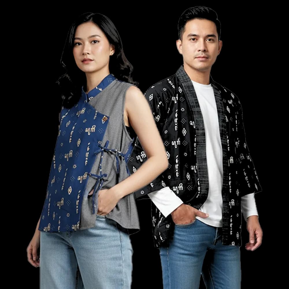 Two Zayru models — a woman in a blue aksara batik vest and a man in a black aksara batik kimono — back-to-back, cut out against the page backdrop.